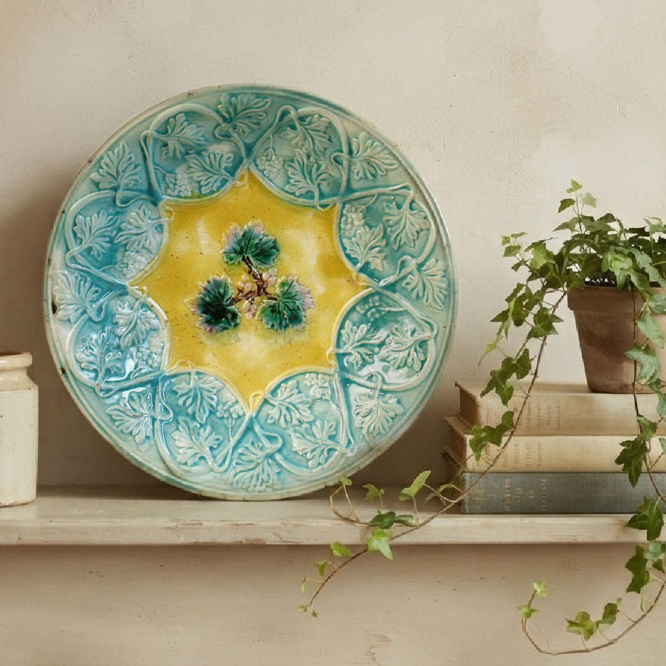 Antique 19th century majolica bowl with leaf and vine decoration on shelf with books and ivy