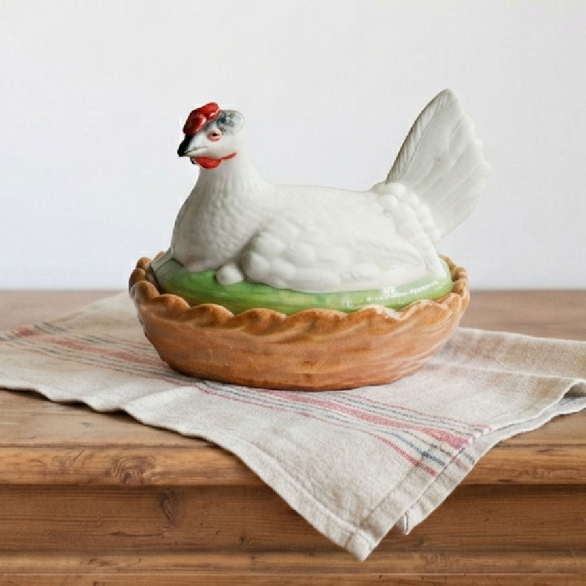 19th century Staffordshire hen on nest tureen showing hand painted details and glazed basket base on an antique french towel on a french dresser.