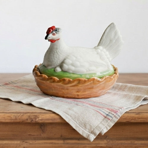 19th century Staffordshire hen on nest tureen showing hand painted details and glazed basket base on an antique french towel on a french dresser.