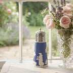 Antique blue and white jasperware muffineer with goddess relief on a table with a crystal vase of pink roses