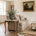 Antique French Garden Urn with classical faces and handles in a living room with a linen sofa