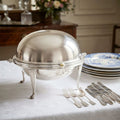 antique Edwardian silver plated revolving dome chafing dish on a table set with antque blue and white plates and silver