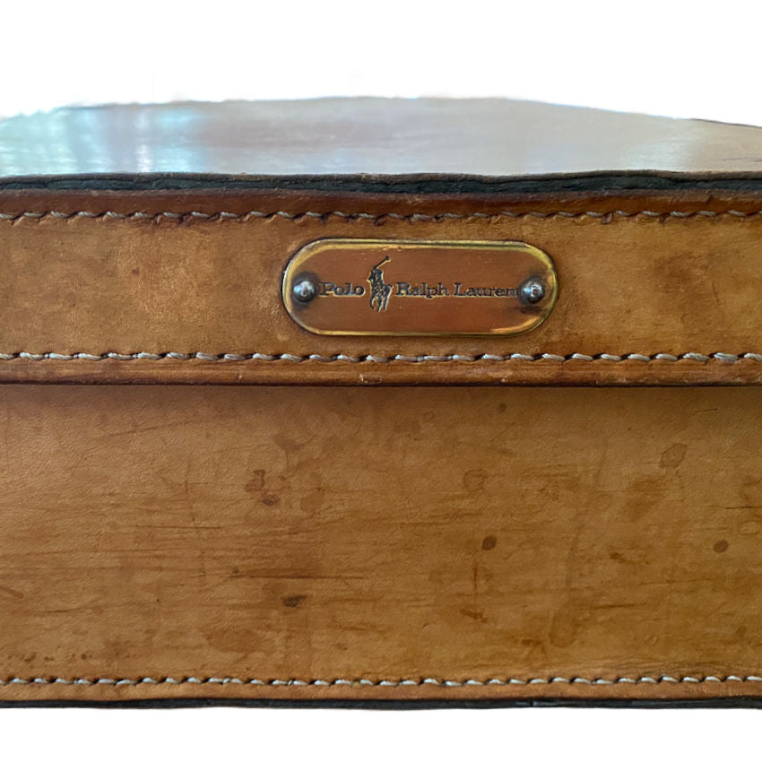 Close-up aged leather suitcase with worn leather and brass Ralph Lauren label