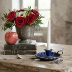 Antique French blue enamelware candle holder styled on an antique wood table with roses and antique books