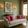 Elegant antique wall sconces for refined European interiors shown with modern painting and linen couch in living room in Paris