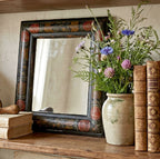 Antique courting mirror with red tulips styled on a shelf with a French vase of flowers and antique books
