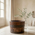 Antique oak bucket styled with fresh Antique oak bucket styled with fresh olive branches on the floor of a bright French country kitchen