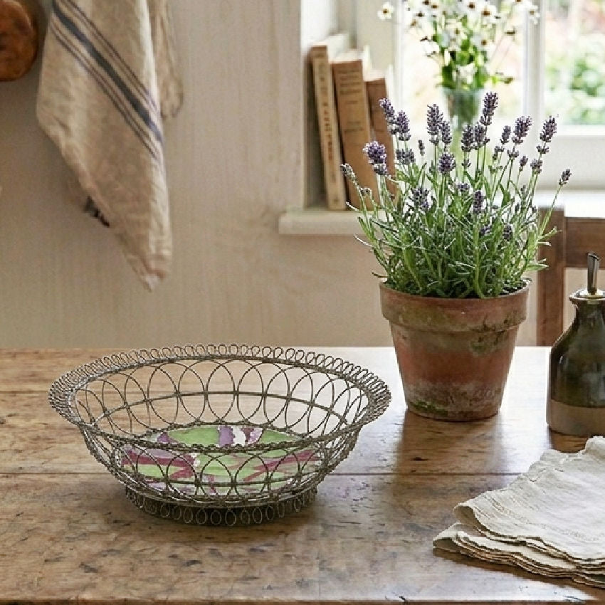 Antique French fil de fer basket with Sarreguemines marbled faience plate styled on rustic wood table with copper, linen, and lavender in natural window light