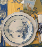 Antique Gien “Oiseaux et Bourgeois” blue transferware plate on a white pottery charger and a yellow and blue chinoiserie French tablecloth.
