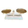 An antique French balance scale with white and aqua blue painted details and two brass weighing trays.