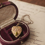 Close-up of antique gold-filled heart locket and repoussé flowers on velvet box