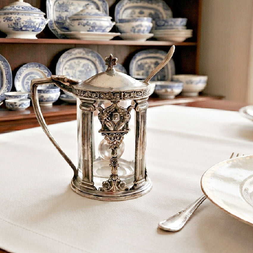 Antique Hotel Deshler silver plate mustard pot with original glass liner and spoon on table with blue and white antique porcelain