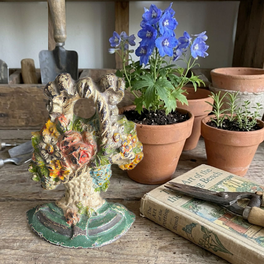 Antique Hubley flower basket doorstop original paint styled with gardening book and vintage garden tools