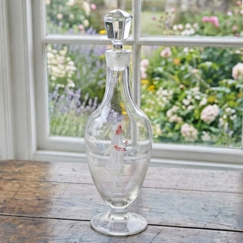 Antique Mary Gregory glass decanter with white enamel figure styled on an antique French cabinet in a country home