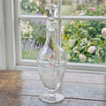 Antique Mary Gregory glass decanter with white enamel figure styled on an antique French cabinet in a country home