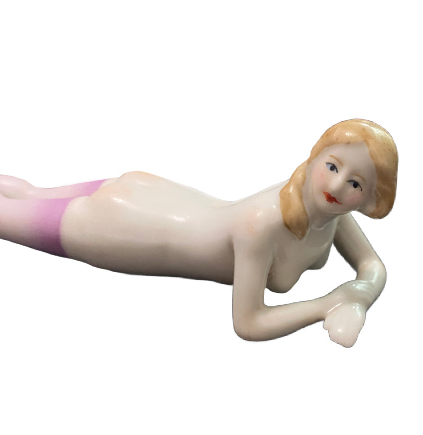 Antique porcelain bathing beauty figurine with lavender stockings. A rare Art Deco–era decorative accent with graceful form and soft pastel detail.