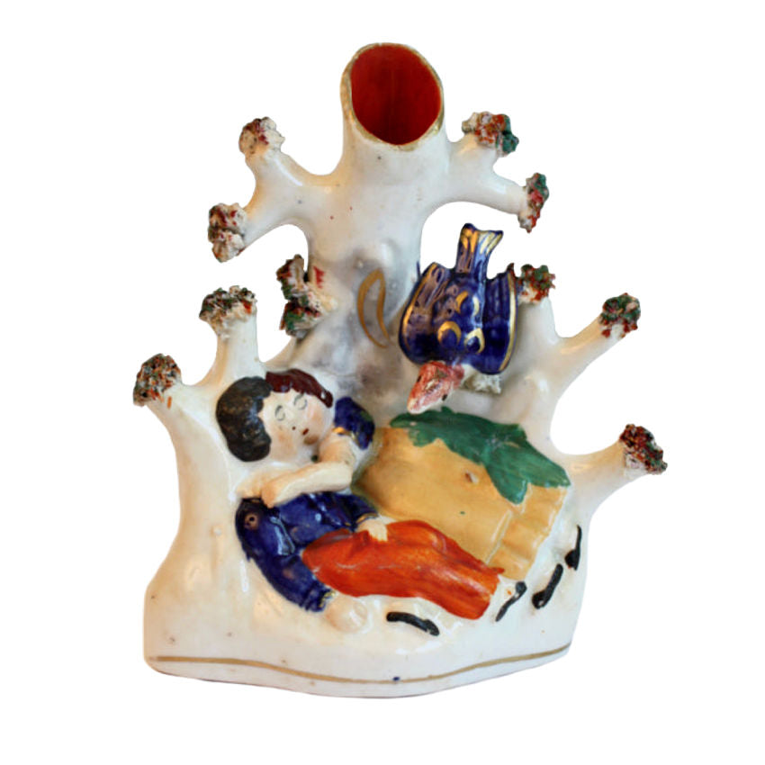 An Early 19th Century Staffordshire Spill Vase featuring a hand-painted scene of a couple sleeping in each other's arms under a tree, with a blue bird and a gray tree trunk.