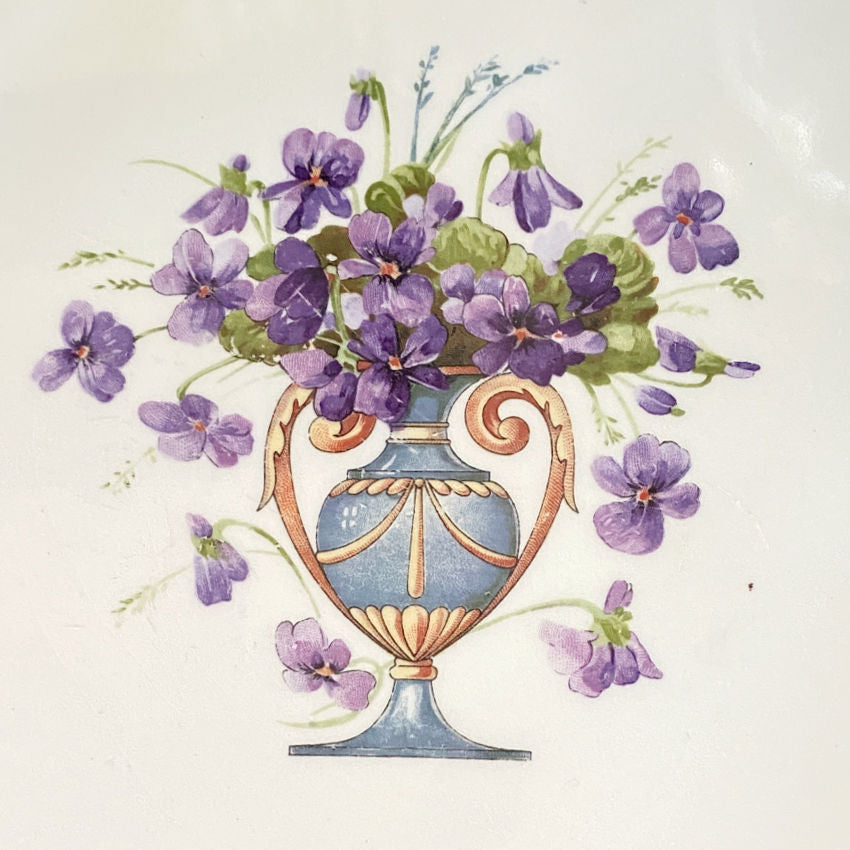 close up of an antique American Wheeling ceramic tile featuring an urn of purple violets. Historic and collectible, perfect as a tea tile, centerpiece, or for a curated tile wall display.