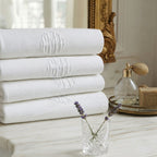 Stack of antique monogrammed cotton piqué guest towels displayed in front of a gold mirror on a French marble bathroom counter