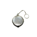 Reverse side striped enamel pattern with subtle scrollwork edging on collectible compact