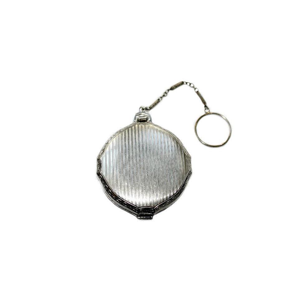 Reverse side striped enamel pattern with subtle scrollwork edging on collectible compact