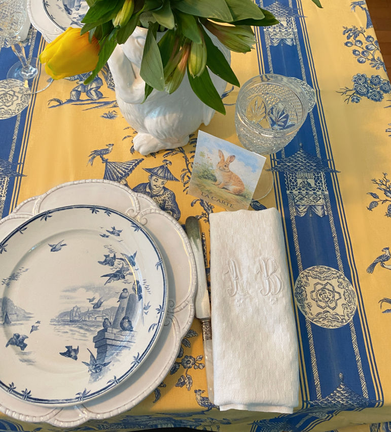 French chinoiserie tablecloth  table setting with antique French blue bird plates and rabbit vase of yellow tulips