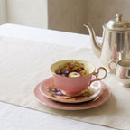 Pink English bone china tea trio styled on white linen with silver tea service