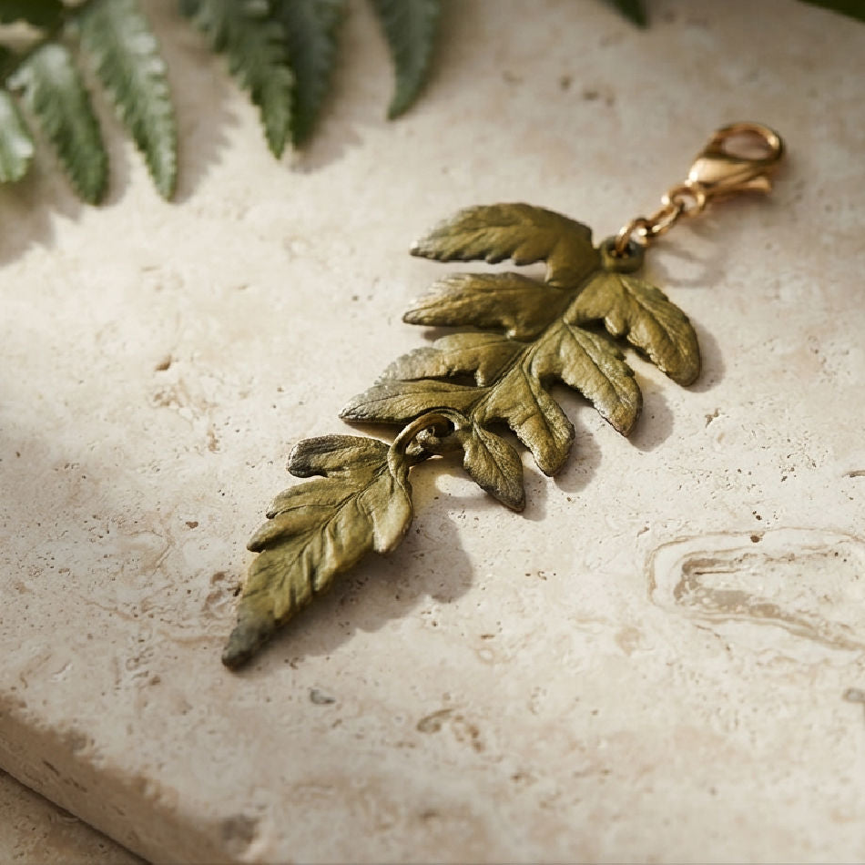 Michael Michaud cast bronze Fern charm on limestone garden bench with fern leaf in background