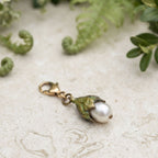 Michael Michaud cast bronze Leaf charm with freshwater pearl on French limestone in a garden setting