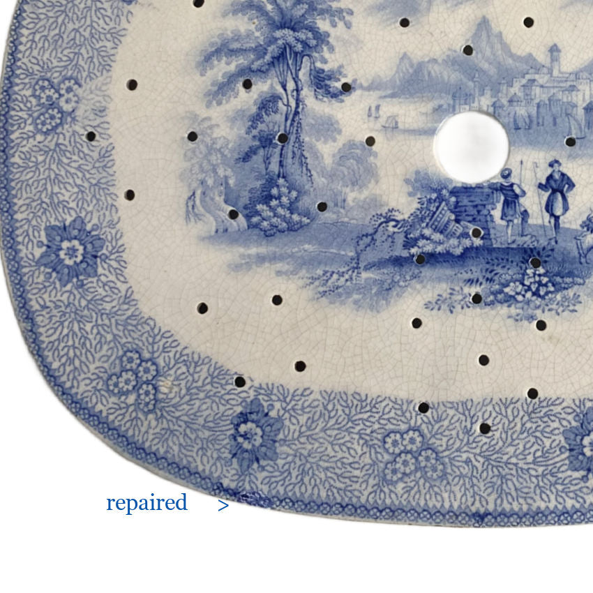 Antique blue and white pottery drainer with subtle professional edge repairs, detail view