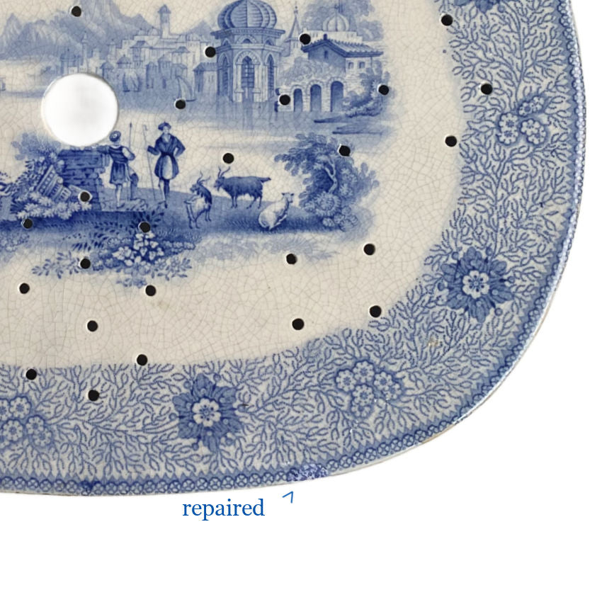 Close up of floral and seaweed border on early 1800s blue and white drainer beautifully repaired