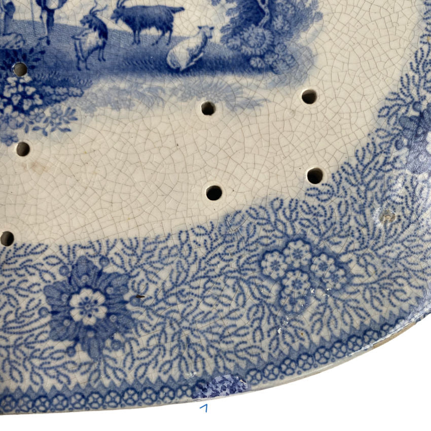 Close up of floral and seaweed border on early 1800s blue and white strainer drainer