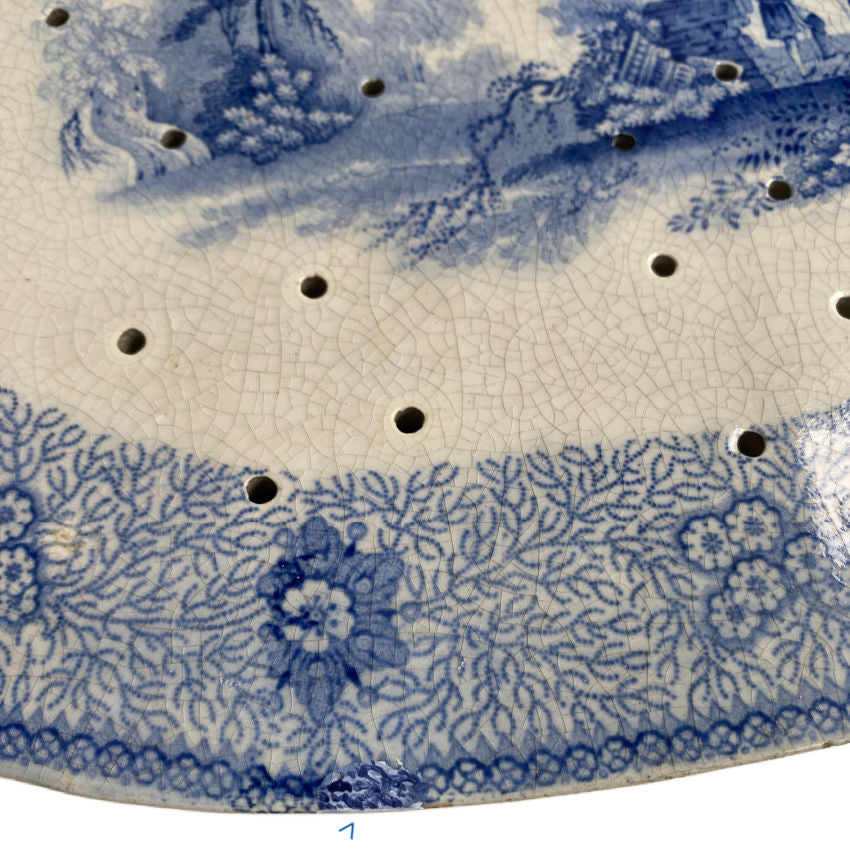 Close up of floral and seaweed border on early 1800s blue and white drainer repaired long ago