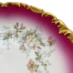 close up of Early 1900s T&V Limoges porcelain plate with pink and yellow roses, cerise pink border, and elaborate gilt scalloped rim.