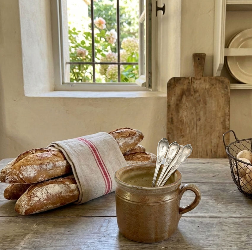 Antique South of France confit pot with warm greige glaze in French country kitchen holding silver spoons