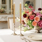 Elderberry branch beeswax taper candles styled in antique silver candlesticks on an elegant dining table with fresh flowers