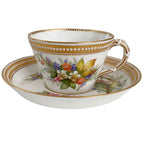 Detail of an antique Royal Worcester cup with its own floral painting, delicate gilding, and raised jeweled ornament