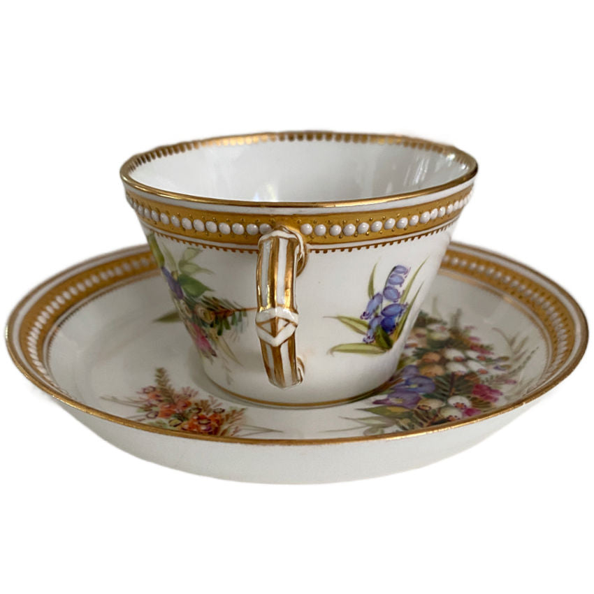 Antique Royal Worcester floral cup and matching saucer showcasing fine hand painting and raised jeweled decoration handle view