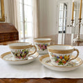 Antique Royal Worcester jeweled cups and saucers with hand-painted flowers on white linen in an elegant French dining room