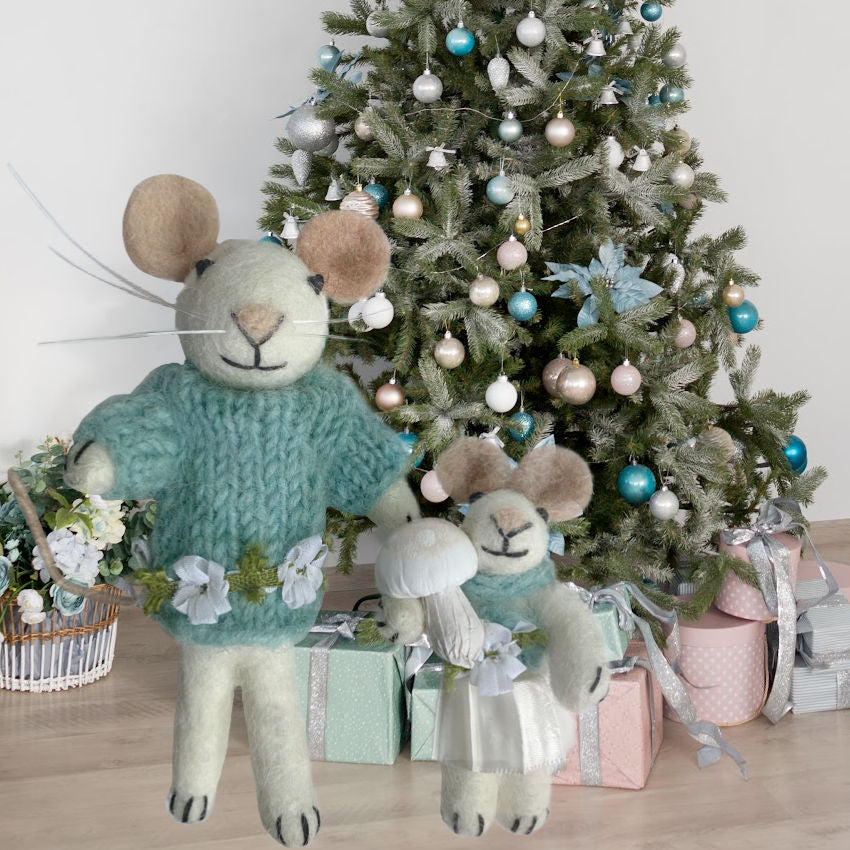 Decorative mouse figurines in front of a Christmas tree with ornaments and presents.