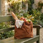 French Country amber bronze linen tote bag on green garden bench with baguette and apples