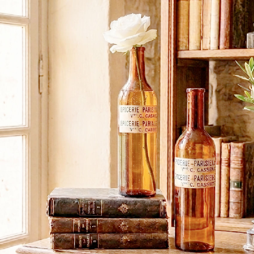 Antique French amber glass bottles with decorative paper labels in natural light