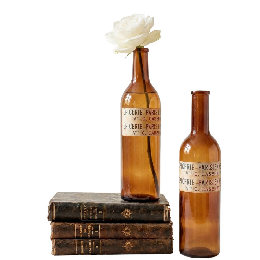 Antique French amber glass bottles with decorative paper labels in natural light