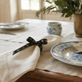 French gold fleur de lis grosgrain ribbon tied around ivory linen napkin set on dinner table with french plates