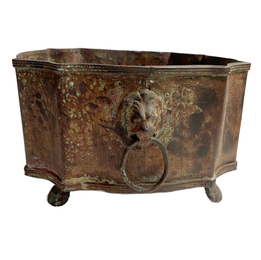 Aged metal planter with lion head handles and paw feet, gracefully weathered patina, rustic elegance, perfect for luxury interiors or garden-inspired décor