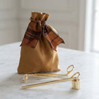 Gold Candle Care Kit with antique gold bag, brass candle snuffer and wick trimmer displayed on marble