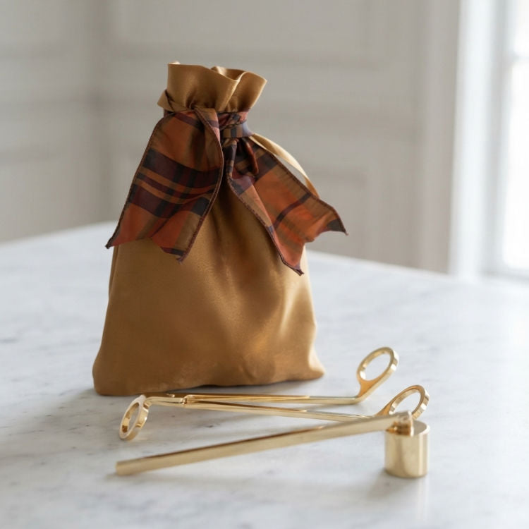 Gold Candle Care Kit with antique gold bag, brass candle snuffer and wick trimmer displayed on marble