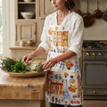 Hand printed Oh La La Paris cotton apron with colorful French landmarks worn on a beautiful woman in her French kitchen