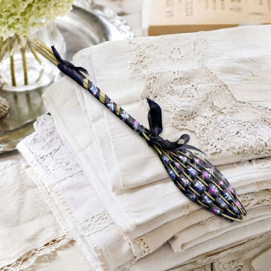 Hand woven French lavender Fuseau de Lavande wand black brocade on stack of antique French linens