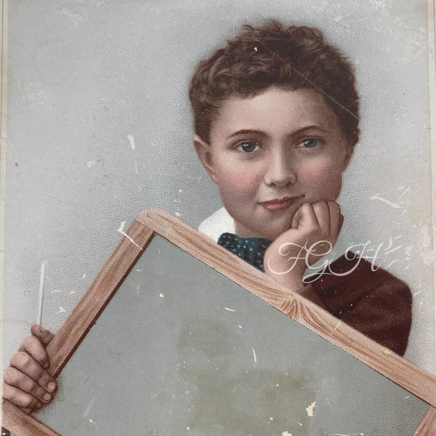 A charming and rare large 19th-century advertising “blank” trade card, featuring a handsome young schoolboy holding an empty slate ready for custom printing or shop branding.